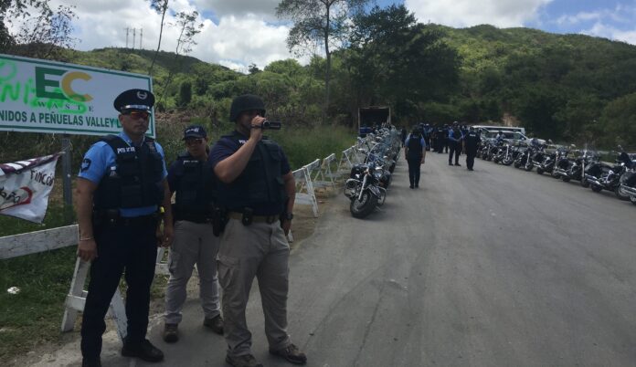 Un agente de la Policía graba las acciones de los manifestantes que se oponen al depósito de cenizas en Peñuelas.