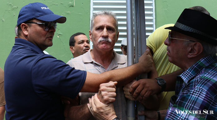El policía municipal Iván Cintrón y otros hombres tratan de remover de la carpa, por la fuerza, a José Torres Vélez. (Voces del Sur / Pedro A. Menéndez Sanabria)