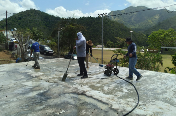Agentes de la Policía realizan trabajos de limpieza en una residencia de Guayama. (Suministrada)